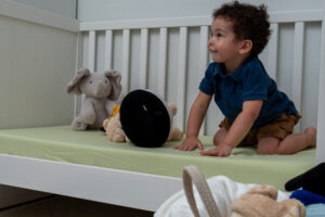 Un bambino seduto nella culla con un lenzuolino verde, sfoglia un libro illustrato.